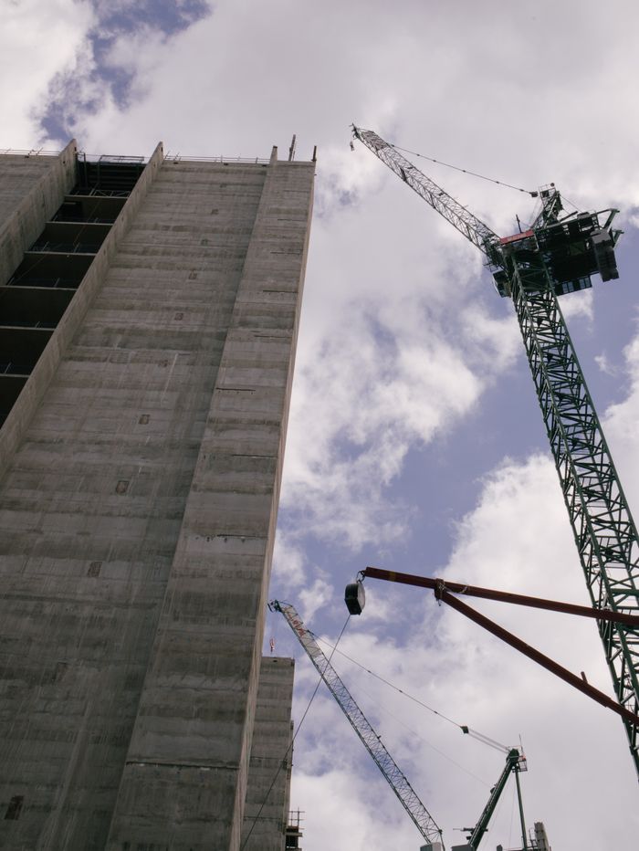 Crafting Captivating Headlines: Your awesome post title goes here Low angle view of skyscraper under construction with cranes against blue sky.