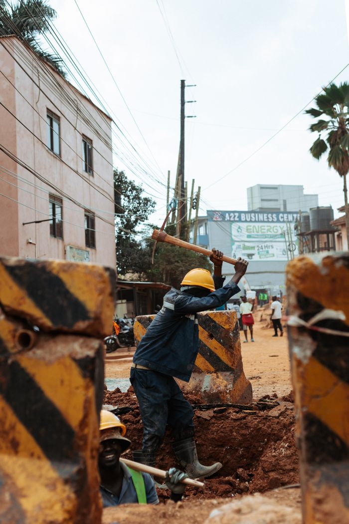 The Art of Drawing Readers In: Your attractive post title goes here Construction worker with hard hat using a pickaxe in an urban street setting, symbolizing infrastructure development.