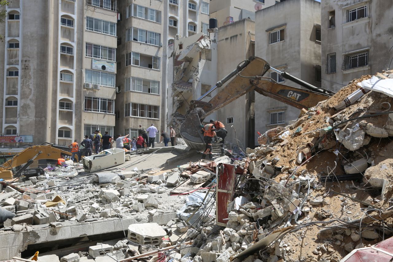 Heavy machinery demolishing urban buildings with workers clearing debris.